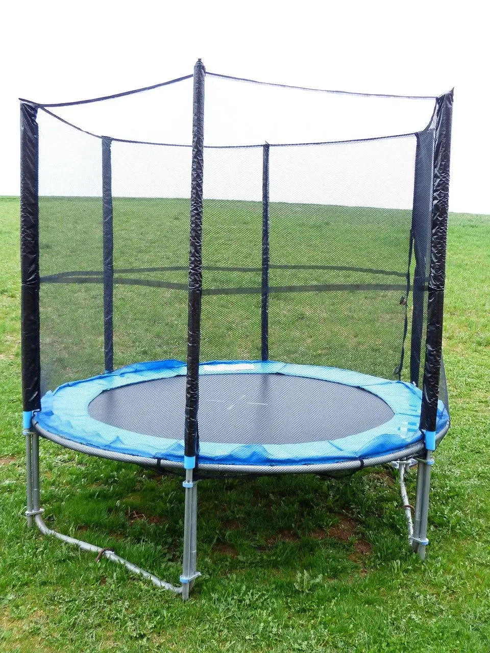 A round garden trampoline with a full safety net enclosure standing on grass