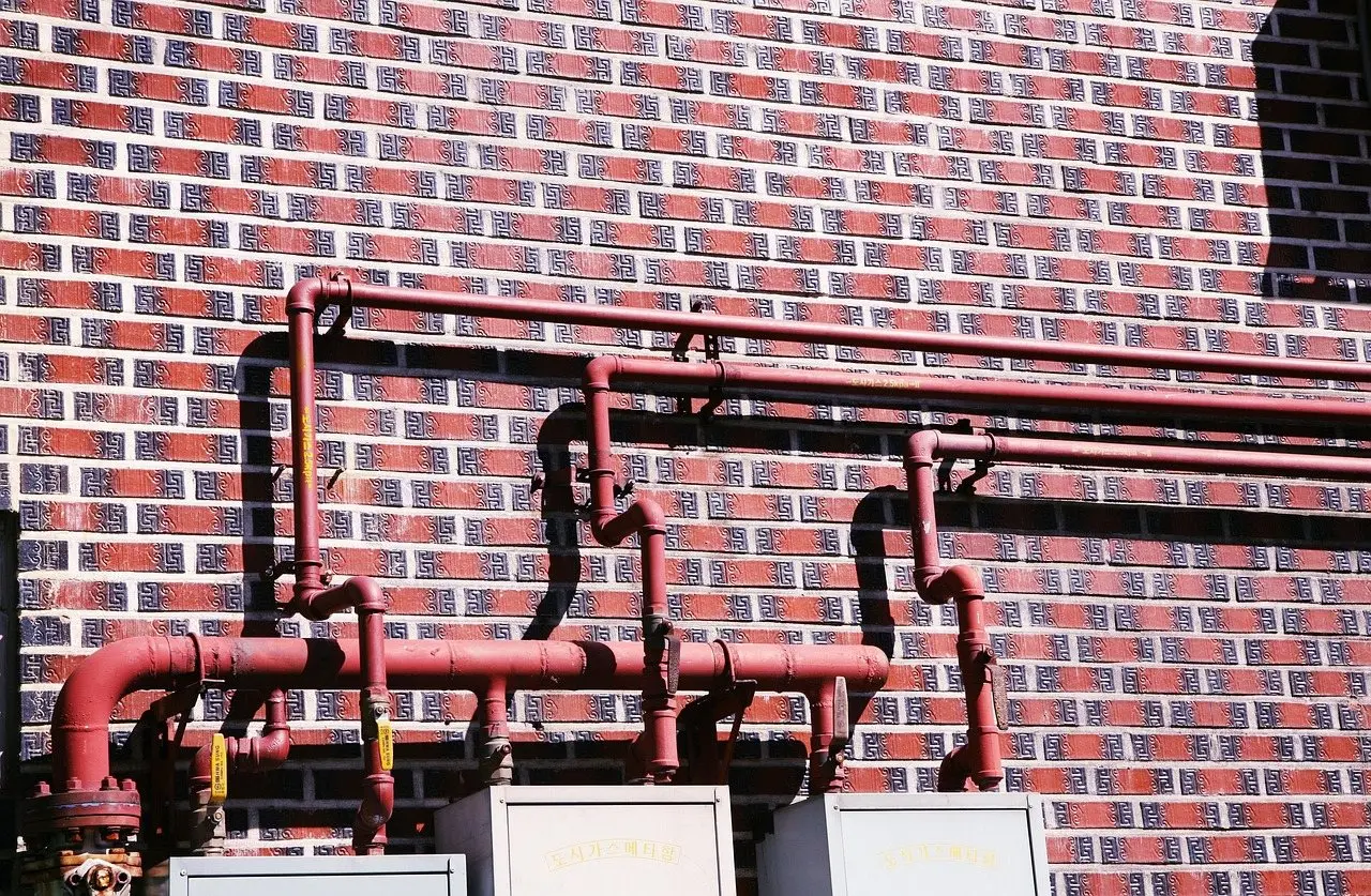 Painted metal vent pipes running up a red brick house wall