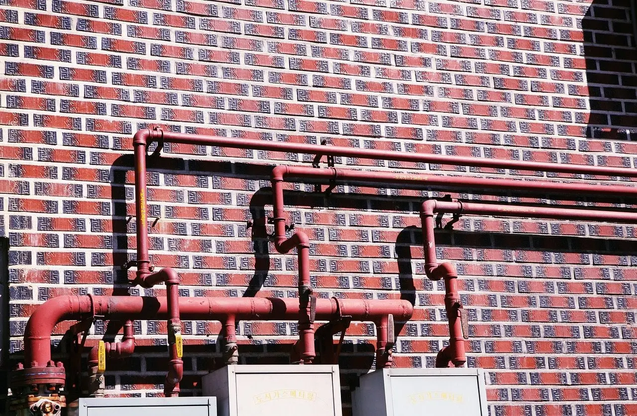 Painted metal vent pipes running up a red brick house wall