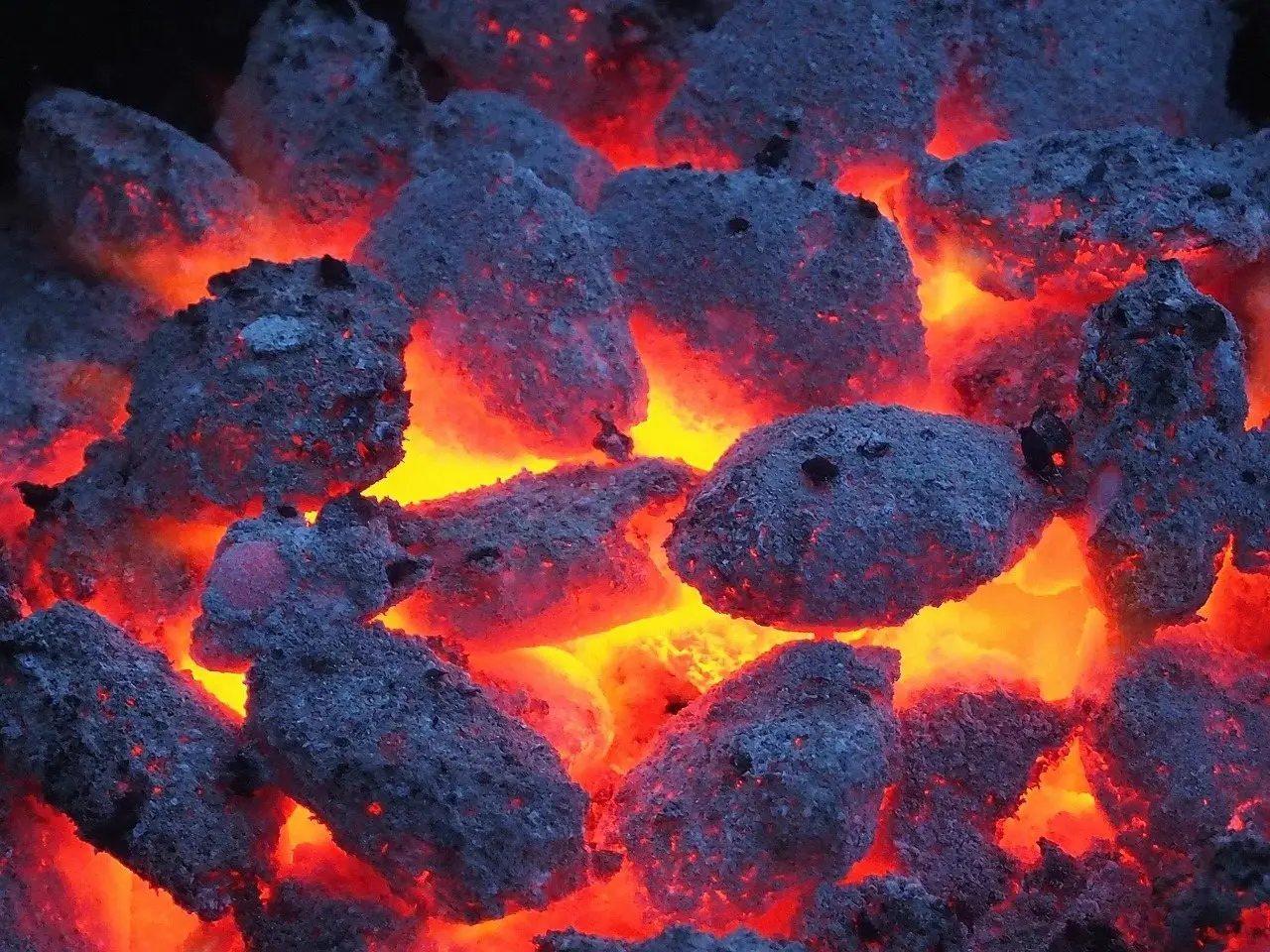 Charcoal briquettes glowing orange under a coating of grey ash