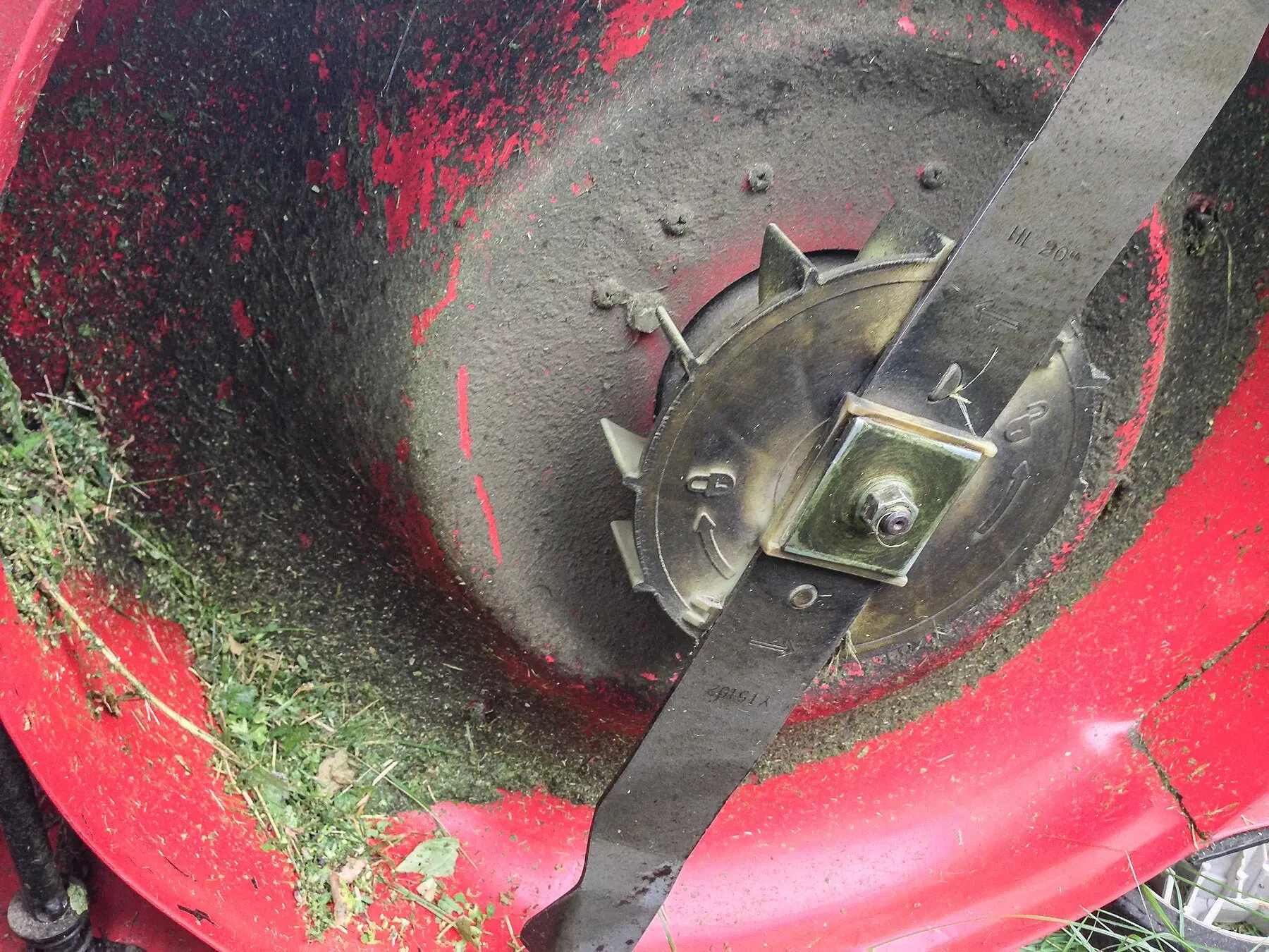 The underside of a mower deck caked with fresh grass clippings