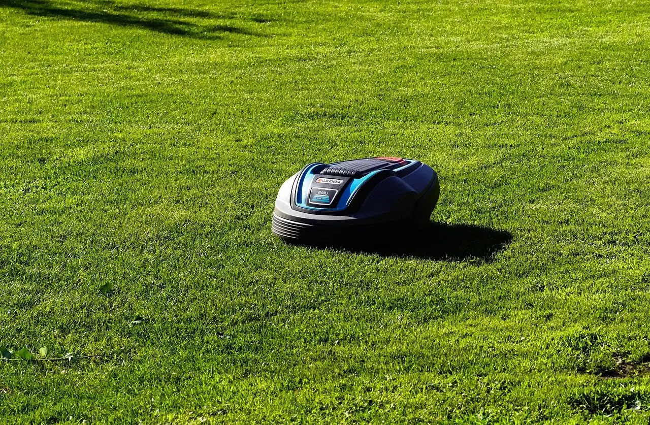 A battery-powered robotic mower working its way across a sunlit lawn