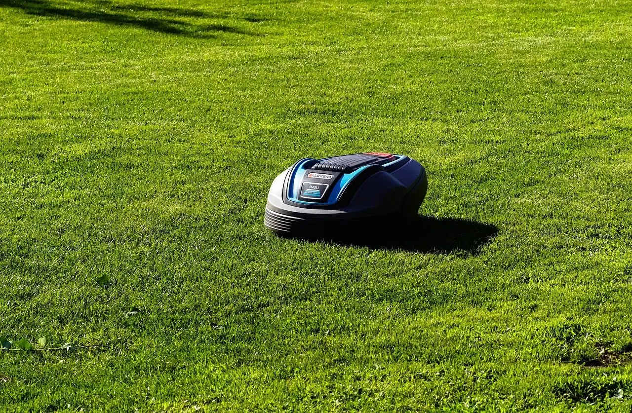 A battery-powered robotic mower working its way across a sunlit lawn