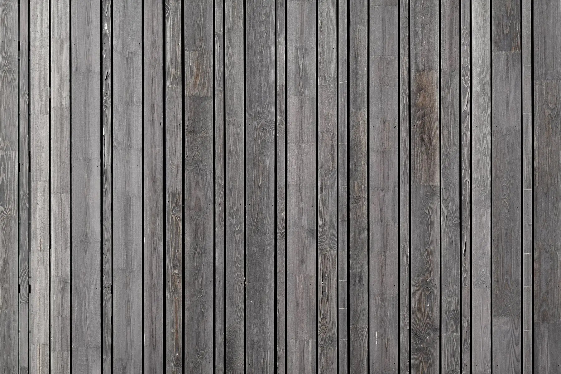 Closely spaced vertical timber fence boards weathered to an even silver-grey