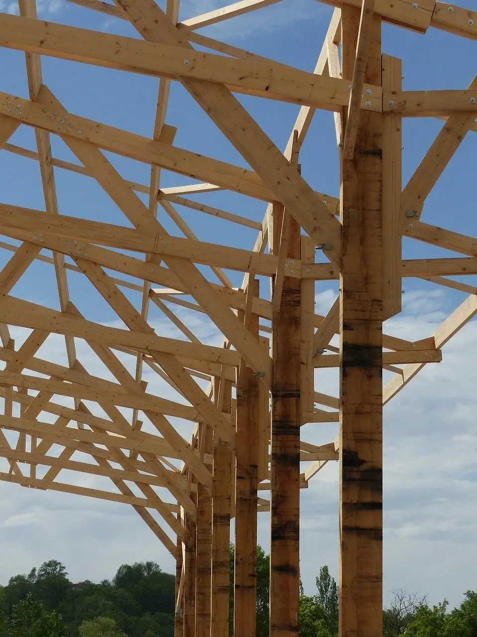A timber roof frame under construction, rafters and bracing exposed against the sky