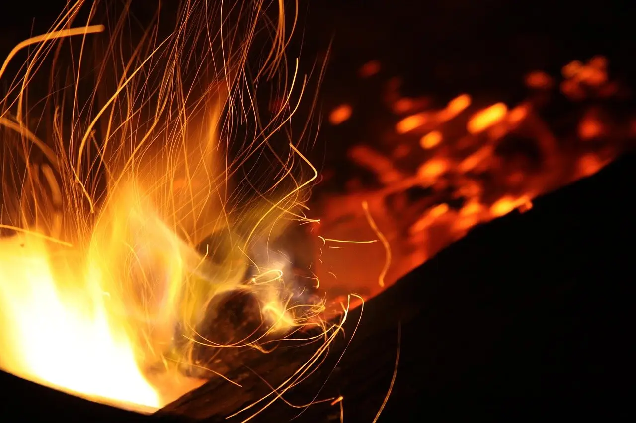 Sparks streaming up from a fire at night in a long exposure