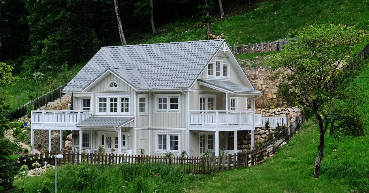 A white timber house with a roofed veranda running along the front, attached to the wall