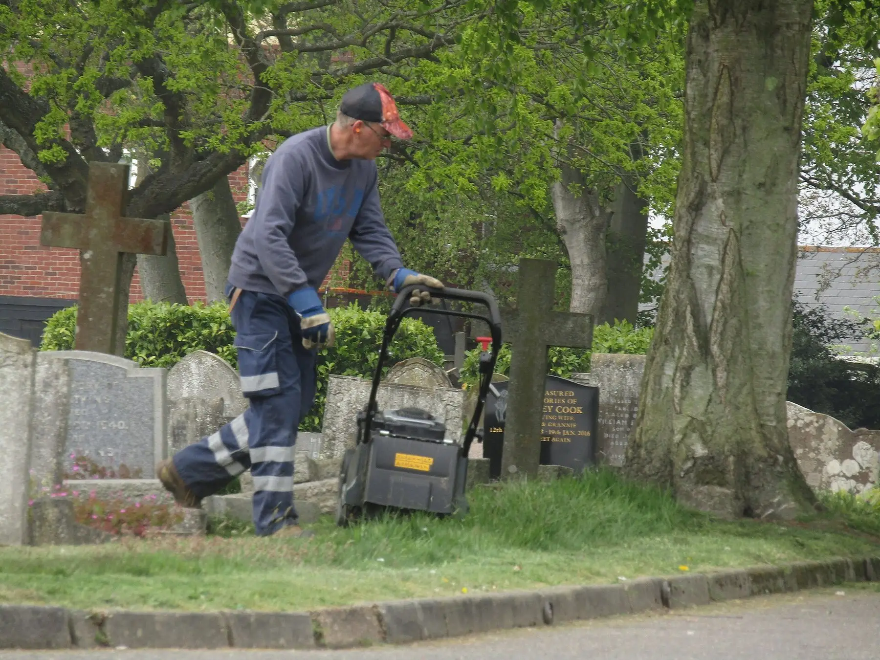Someone walking a push mower across a lawn