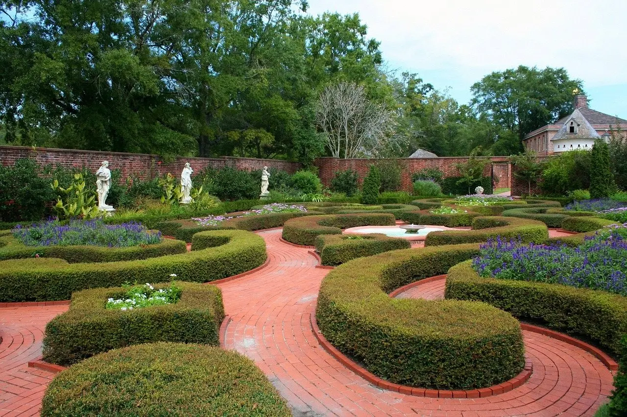 A formal knot garden of clipped box hedging with brick paths, statues and a central fountain