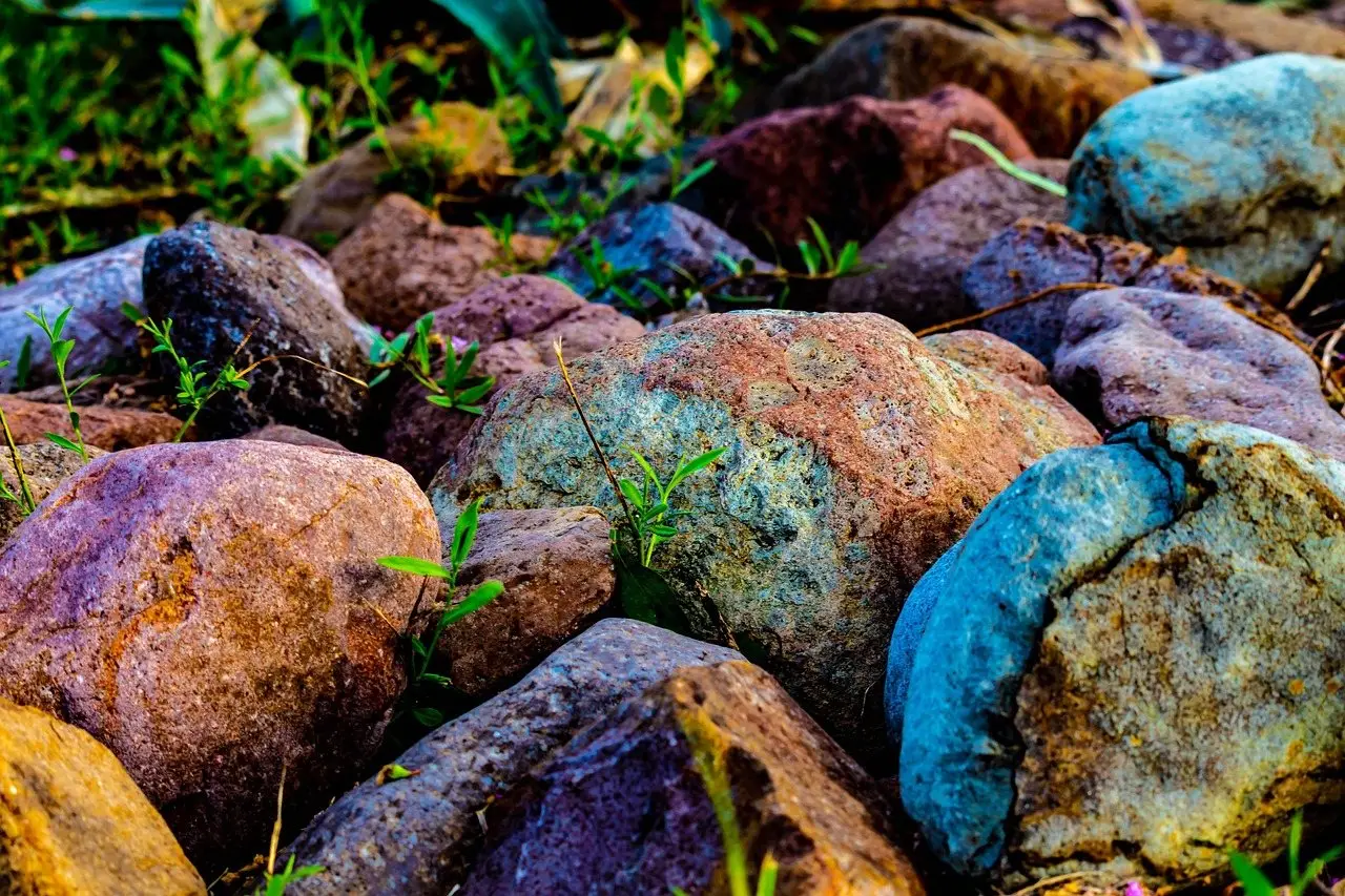 A close view of rounded landscape stones in mixed blue, purple, rust and buff tones