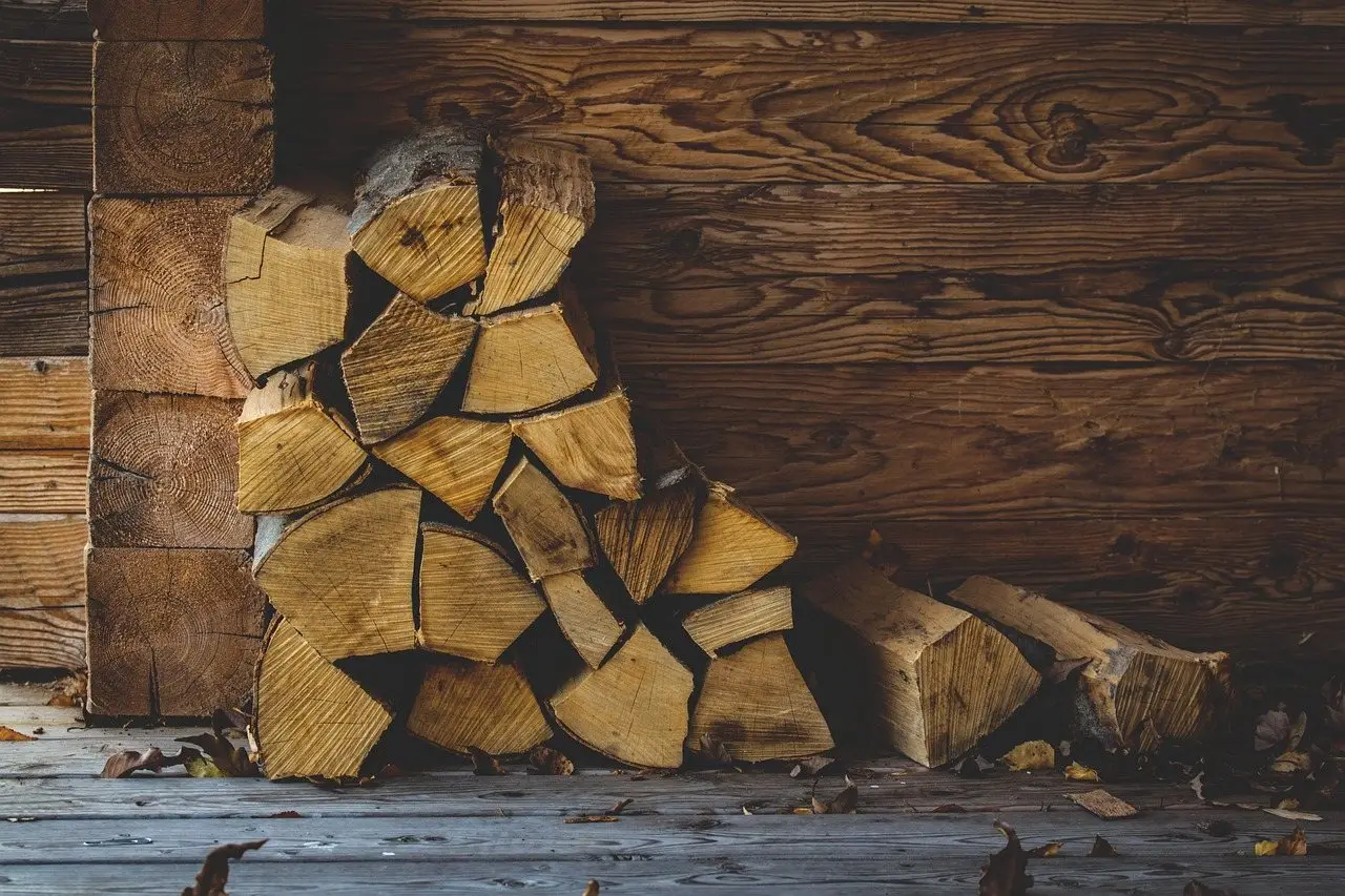 Split logs stacked in a neat row against a weathered timber wall