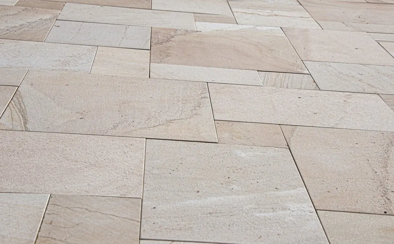 Pale sandstone paving slabs laid in a random rectangular pattern