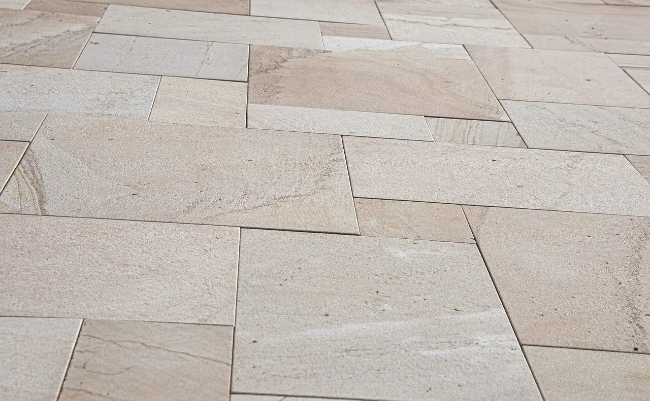 Pale sandstone paving slabs laid in a random rectangular pattern
