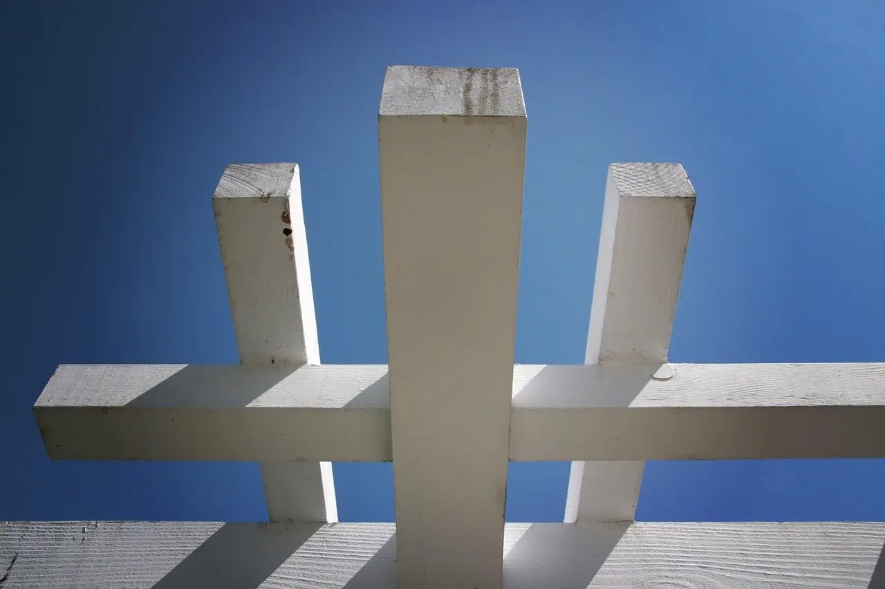 Looking up at a white painted pergola post where the cross beams are notched and lapped over it