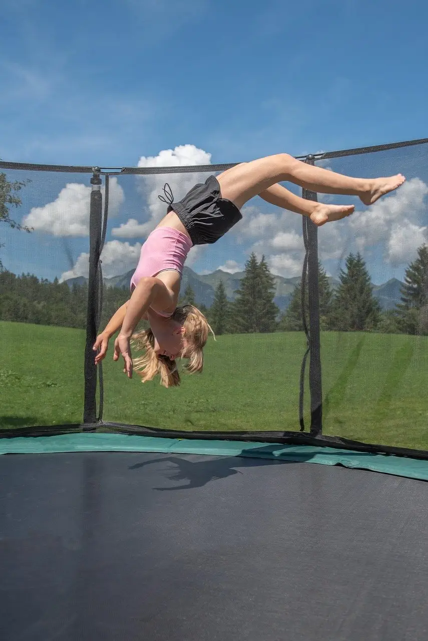 A jumper inverted in mid-air above an enclosed garden trampoline