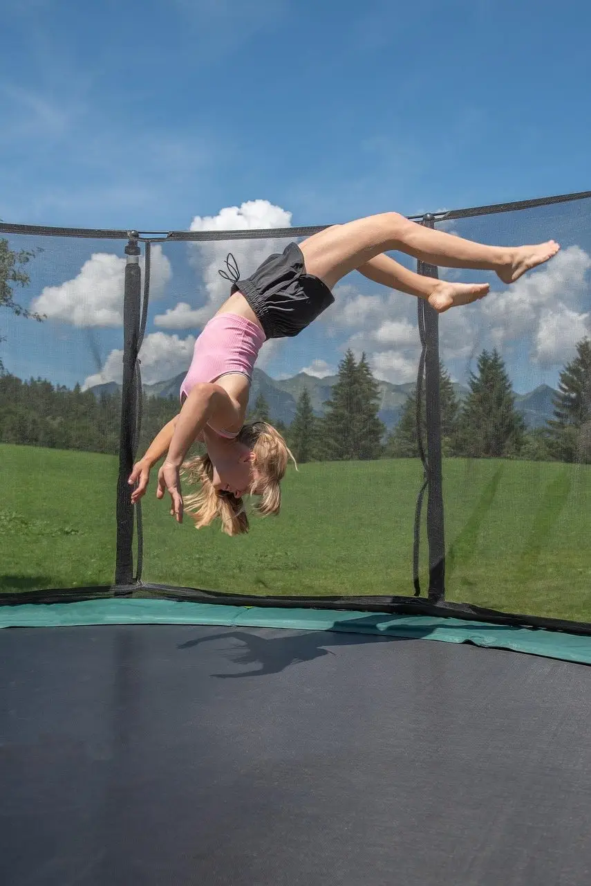A jumper inverted in mid-air above an enclosed garden trampoline