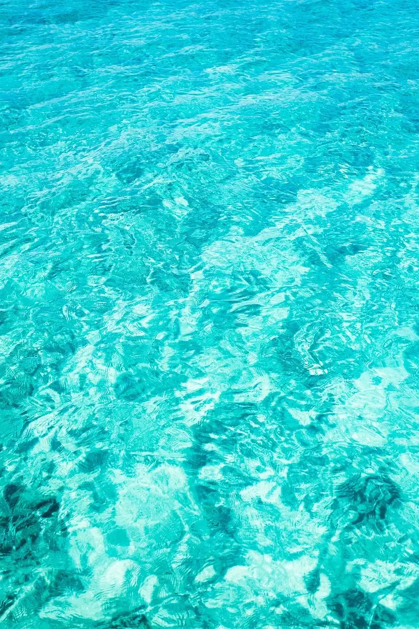 Clear turquoise pool water with sunlight rippling across the surface