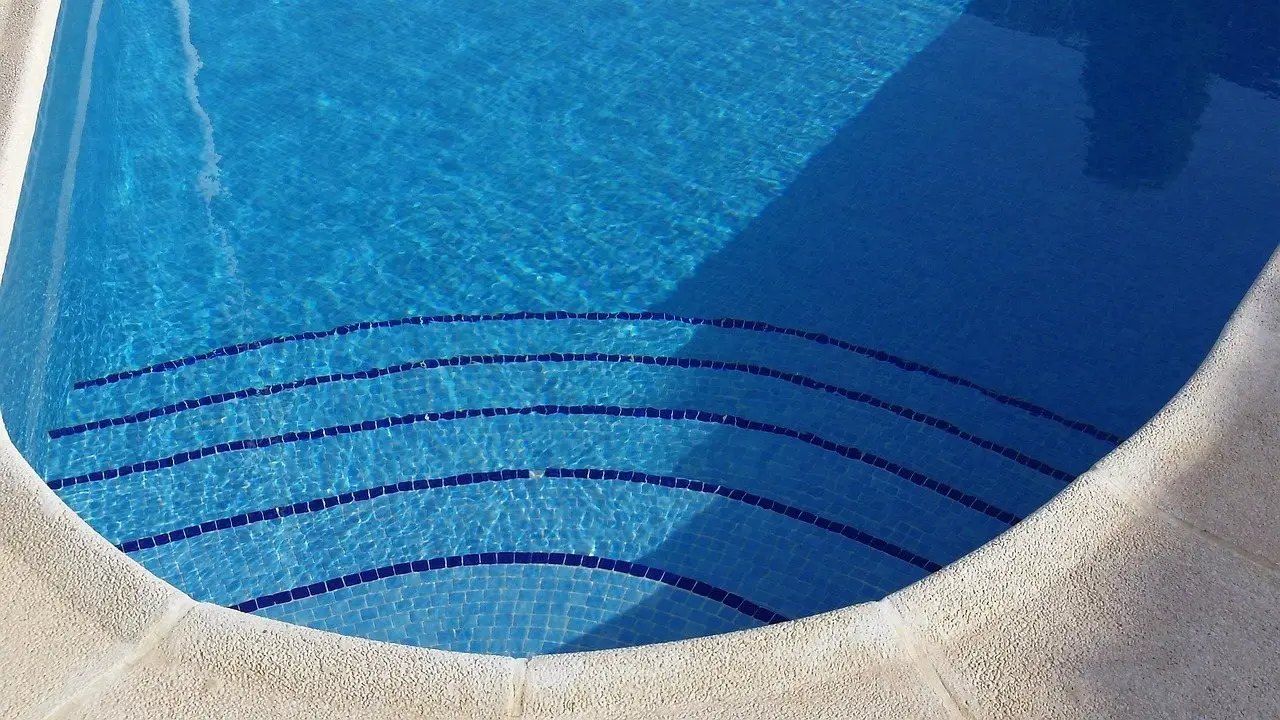 Tiled steps leading into the blue water of a pool, seen from above